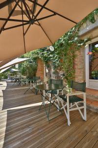 eine Terrasse mit Tischen, Stühlen und einem Sonnenschirm in der Unterkunft Hotel Le Mas Trilles in Céret