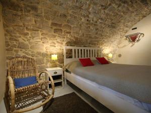 1 dormitorio con cama y pared de piedra en La Salamandre, en Lablachère