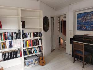 una habitación con estanterías blancas llenas de libros y un piano en Embracing nature's Swedish house, en Ludvika