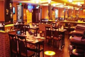 a restaurant with tables and chairs and a bar at Hotel New Ashiyana Palace Inn Varanasi in Varanasi