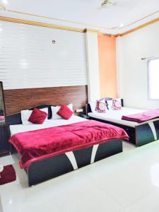 two beds in a room with red and white at Hotel New Ashiyana Palace Inn Varanasi in Varanasi