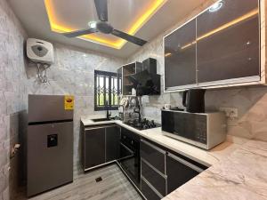 a kitchen with stainless steel appliances and a ceiling fan at CMP APARTMENTS in Kasoa