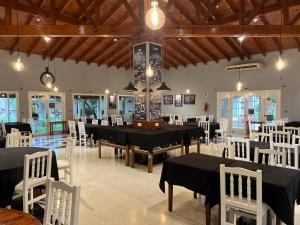 a dining room with black tables and white chairs at Garden House Hotel in Río Cuarto