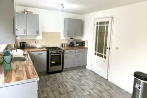 a kitchen with white cabinets and a black stove top oven at Comfy Room in Nottingham in Nottingham