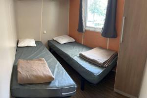 two beds in a small room with a window at Mobil Home 3 chambres in Biesheim