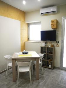 Una habitación con una mesa y sillas y un televisor. en SIKELIA LUXURY ROOMS, en Agrigento