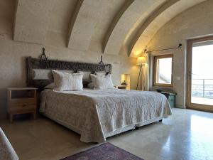 a bedroom with a large bed and a large window at Kistar Cave Hotel in Uchisar