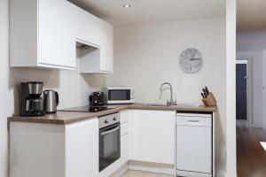 una cocina con armarios blancos y un reloj en la pared en One-Bedroom Apartment in Conditioning House, en Bradford