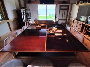七尾市にある能登島ゲストハウスうたたねのダイニングルーム付きの客室で、大きな木製テーブルが備わります。