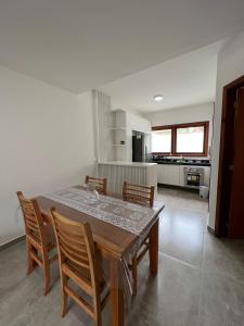 a dining room table with chairs and a kitchen at Casa Maritaca in Paraty