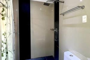 a bathroom with a toilet and a glass shower door at Sheryll Updates - Kandi T2 breezy 1BR on 9th floor with Housekeeping & Netflix in Angeles +7 photos