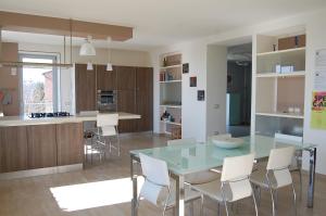 een keuken met een glazen tafel en witte stoelen bij Monferrato Asti-luminosa villa in CastellʼAlfero