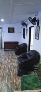 una sala de estar con 2 sillas de cuero negro y un piano en KANTHI GUEST INN, en Trincomalee