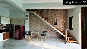 a dining room with a table and a staircase at Nessies Nagaon in Alibaug