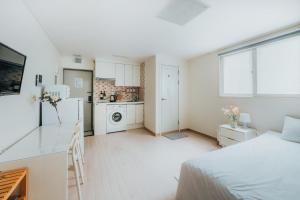 um quarto branco com uma cama e uma cozinha em DK House em Seul