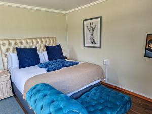 a bedroom with a large bed with blue cushions at Lilitha Boutique Hotel-East London in East London