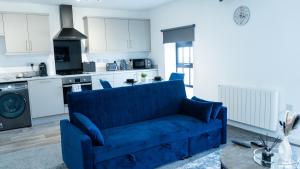 a blue couch in a living room with a kitchen at 1BR Sleeps 4, 3 mins from City centre & Local Gems in Burton upon Trent