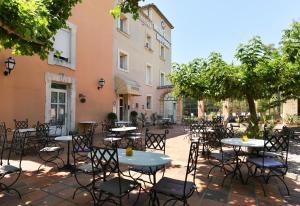 un patio avec des tables et des chaises en face d'un bâtiment dans l'établissement The Originals City, Hôtel du Parc, Avignon Est (Inter-Hotel), à Entraigues-sur-la-Sorgue