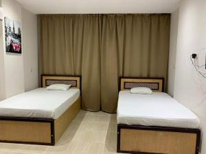 two twin beds in a room with curtains at شاليه داخل ميراج اكوا بارك in Hurghada