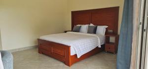 a bedroom with a large bed with a wooden headboard at Kaije Country Cottages in Fort Portal