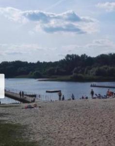 a group of people on a beach near a lake at Zacisze 6 osobowy Domek nad jeziorem in Świętne