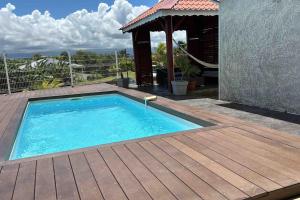 a swimming pool with a wooden deck and a gazebo at Villa Fusains in Baie-Mahault +4 photos