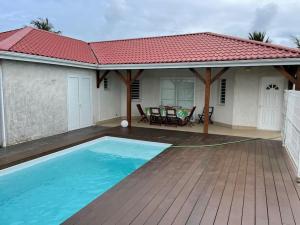 a house with a swimming pool and a red roof at Villa Fusains in Baie-Mahault