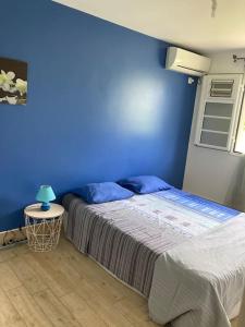 une chambre bleue avec un lit et une table avec une lampe dans l'établissement Villa Fusains, à Baie-Mahault