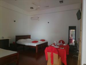 une chambre avec un lit et une table avec un tissu de table rouge dans l'établissement Avanya Hotel And Reception Hall, à Angunakolapelessa