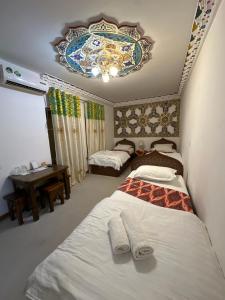 1 dormitorio con 2 camas y techo con lámpara de araña. en Rizo Boutique, en Bukhara