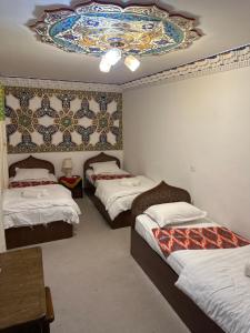 Habitación con 3 camas y techo con lámpara de araña. en Rizo Boutique en Bukhara