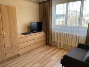 uma sala de estar com uma televisão numa cómoda com uma janela em Centra dzīvoklis em Jelgava