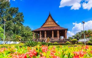 a pagoda in a park with flowers in the foreground at Thavixay Hotel 博雅酒店酒店 in Vientiane