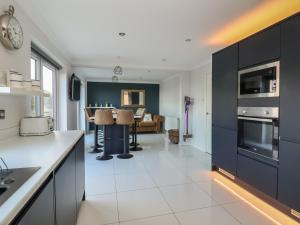 a kitchen with black cabinets and a living room at 107 Gronant Road in Prestatyn