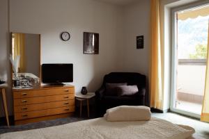 a bedroom with a tv and a chair and a dresser at Garni Unterwegguetl in Naturno