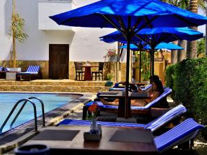 a group of people sitting in lounge chairs next to a pool at St.Lachlan Hotel & Suites in Negombo