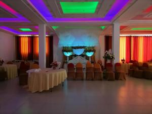 une salle de banquet avec des tables, des chaises et des lumières violettes dans l'établissement Avanya Hotel And Reception Hall, à Angunakolapelessa