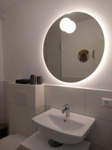 La salle de bains blanche est pourvue d'un lavabo et d'un miroir. dans l'établissement La Dolce Casa bei Hamburg, à Seevetal