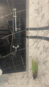 y baño con ducha y azulejos blancos y negros. en Хотел Враца, en Vratsa