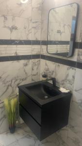 baño con lavabo negro y espejo en Хотел Враца en Vratsa