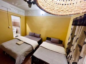 two beds in a small room with a bathroom at Paris Guest House in Bharatpur
