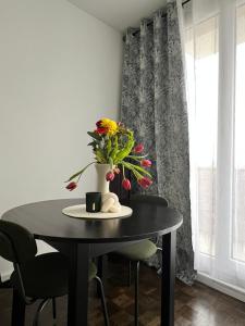 une table noire avec un vase de fleurs sur elle dans l'établissement Paris Appartement - Calm with a balcony, parking, 15 min from Paris and Orly airport, 30 min from Disneyland, à Antony