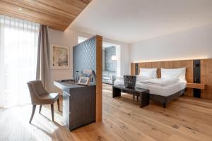 a hotel room with a bed and a desk and a chair at Waldhotel Arosa in Arosa