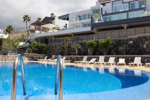 a swimming pool with chairs and a building at Azure Sky Villa - Panoramic ocean view, luxury, San Eugenio in Adeje