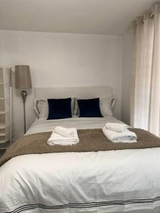 Una cama blanca con dos toallas encima. en Central entire studio apartment en Londres