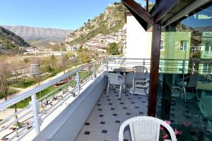 a balcony with a table and chairs and mountains at Hotel & Restaurant White City in Berat