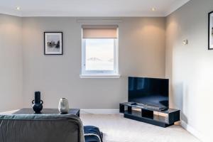 Penthouse at the Bay near Edinburgh في Saint Davids: غرفة معيشة مع تلفزيون بشاشة مسطحة وأريكة