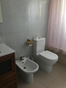 a white bathroom with a toilet and a sink at Chalet de la playa in Oropesa del Mar
