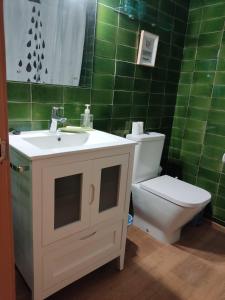 een badkamer met een wastafel, een toilet en groene tegels bij Voramar D- Estudi in Calella de Palafrugell