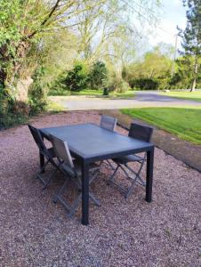 una mesa negra con dos sillas sentadas a su alrededor en Maison traditionnelle Normande avec piscine, en Hotot-en-Auge